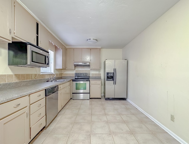 kitchen with a sink, under cabinet range hood, light countertops, light tile patterned flooring, and stainless steel appliances