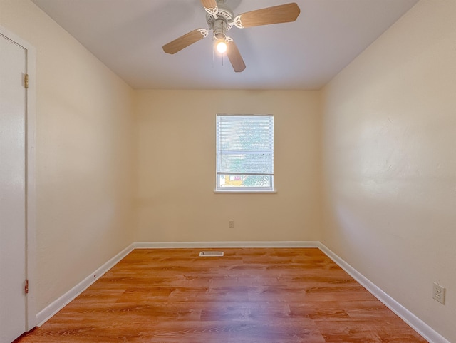 empty room with baseboards, a ceiling fan, and light wood finished floors