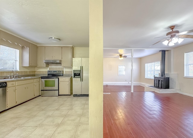 kitchen featuring open floor plan, cream cabinetry, a sink, under cabinet range hood, and stainless steel appliances