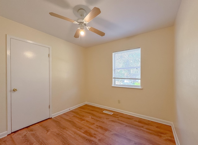 empty room with baseboards, a ceiling fan, visible vents, and light wood-type flooring