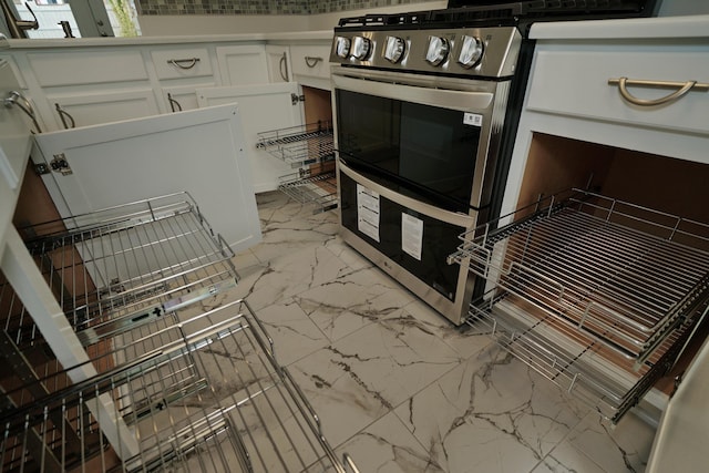 kitchen featuring stainless steel range and white cabinets