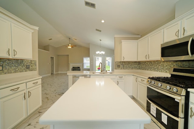 kitchen featuring decorative backsplash, a center island, stainless steel appliances, and ceiling fan