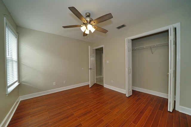 unfurnished bedroom featuring dark hardwood / wood-style floors, ceiling fan, and a closet