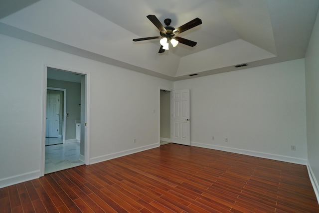 unfurnished room featuring dark hardwood / wood-style flooring, a raised ceiling, and ceiling fan