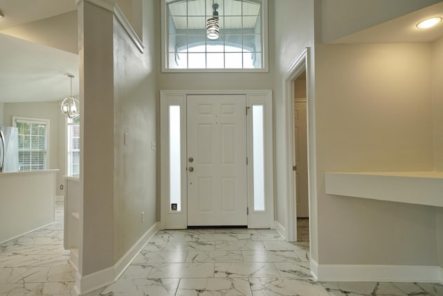 foyer with a wealth of natural light, high vaulted ceiling, and an inviting chandelier