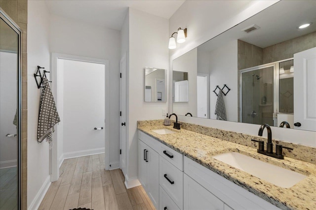 full bath featuring a shower stall, wood finished floors, visible vents, and a sink