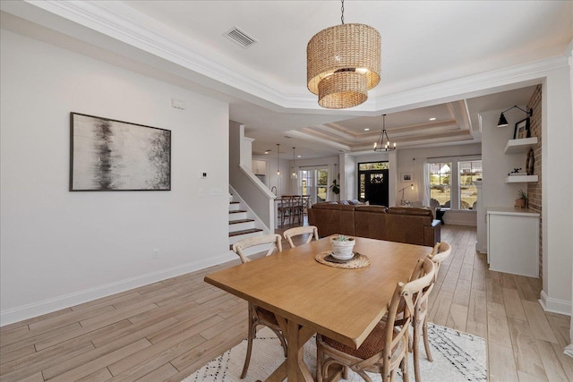 dining area with visible vents, a tray ceiling, crown molding, light wood-type flooring, and a chandelier