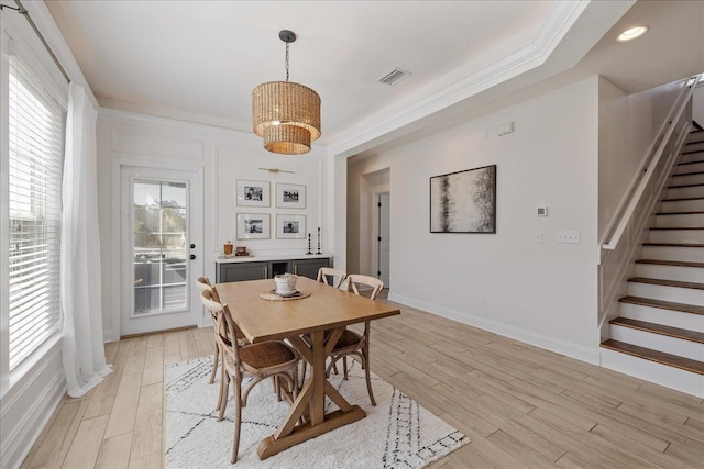 dining room with visible vents, stairway, light wood-style floors, crown molding, and baseboards