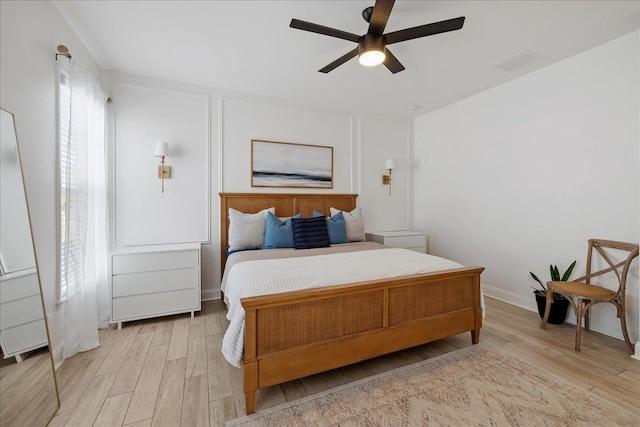 bedroom featuring baseboards, visible vents, light wood finished floors, and ceiling fan