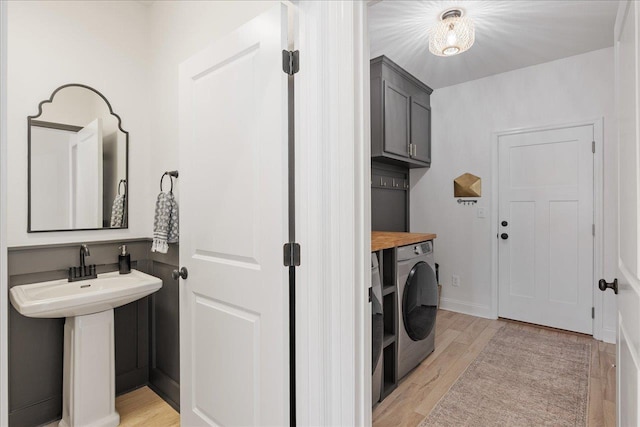 washroom with cabinet space, light wood-style flooring, and baseboards