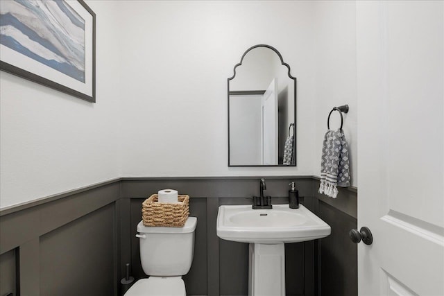bathroom featuring a sink, toilet, and wainscoting