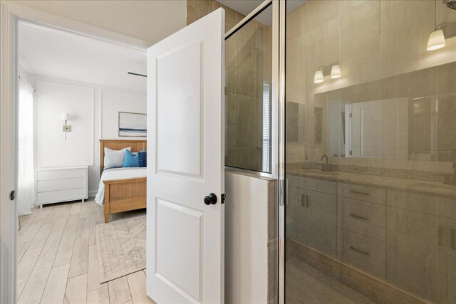 bathroom with wood finish floors, ensuite bath, a stall shower, and vanity