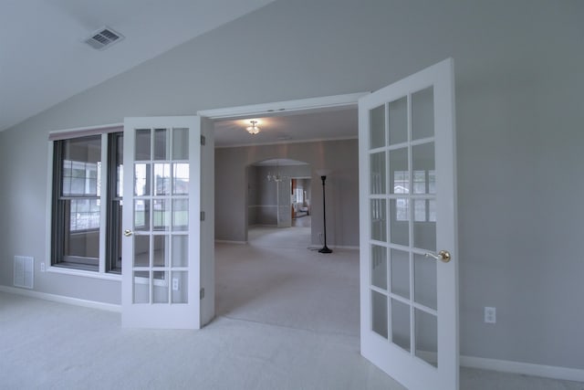 carpeted empty room featuring lofted ceiling and french doors