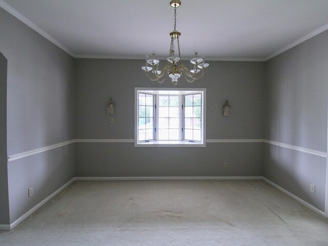 carpeted spare room featuring ornamental molding and a notable chandelier