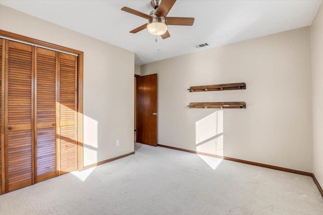 unfurnished bedroom with ceiling fan, light colored carpet, and a closet