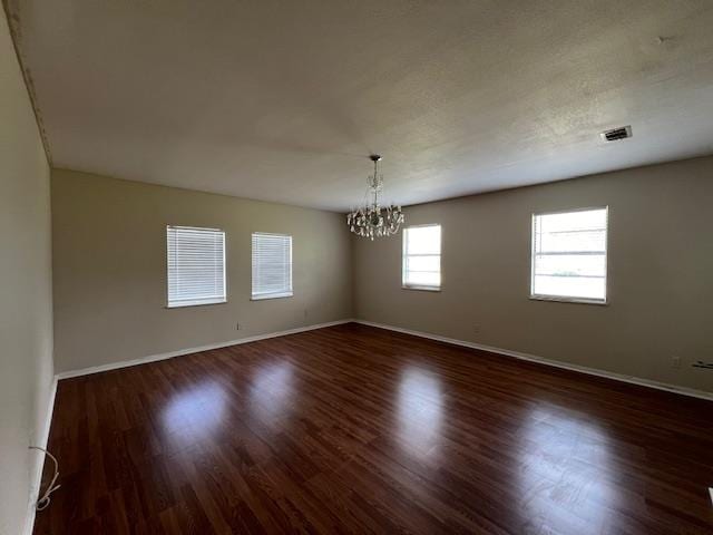 unfurnished room featuring dark hardwood / wood-style flooring and a notable chandelier