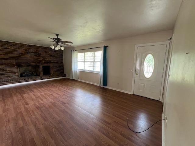 foyer entrance featuring a fireplace, dark hardwood / wood-style floors, and ceiling fan