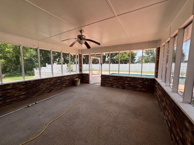 unfurnished sunroom featuring ceiling fan