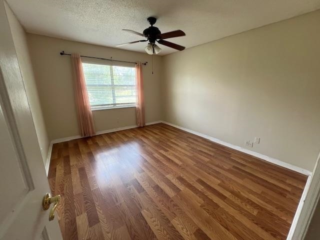 spare room featuring a textured ceiling, wood-type flooring, and ceiling fan