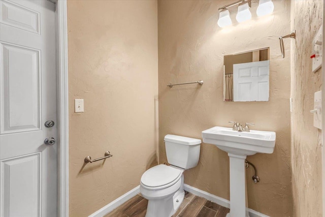 bathroom featuring toilet, wood finished floors, and baseboards