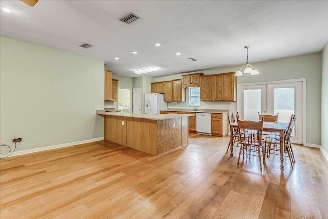 kitchen with a sink, an inviting chandelier, recessed lighting, white appliances, and a peninsula