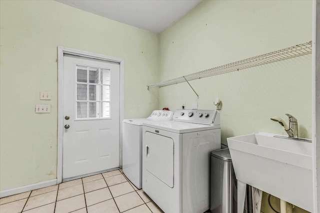 clothes washing area featuring light tile patterned flooring, washer and clothes dryer, laundry area, and a sink