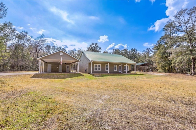 view of front of home featuring metal roof, a front yard, driveway, and a detached carport