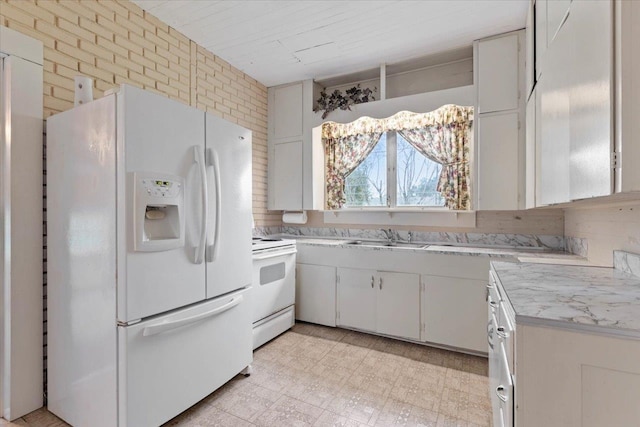 kitchen with sink, white cabinets, brick wall, and white appliances