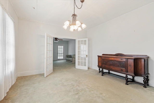 interior space featuring french doors, light colored carpet, and ceiling fan with notable chandelier