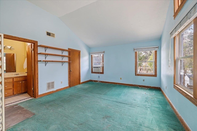 unfurnished bedroom with connected bathroom, sink, high vaulted ceiling, cooling unit, and carpet