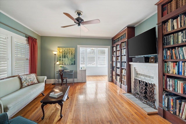 living room featuring a tiled fireplace, crown molding, and light hardwood / wood-style flooring