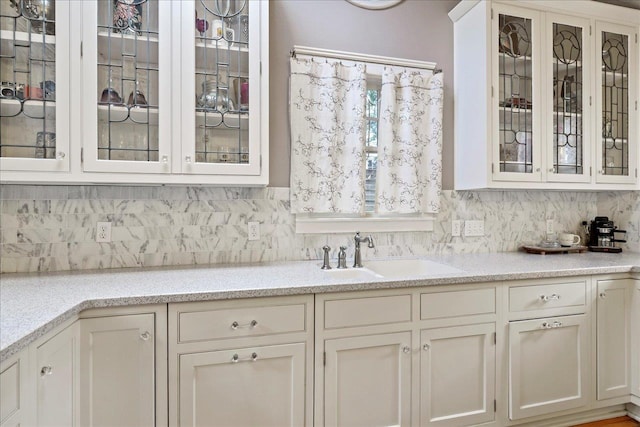 bar featuring light stone countertops, sink, white cabinets, and decorative backsplash