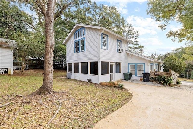 rear view of property featuring cooling unit, a yard, and a sunroom