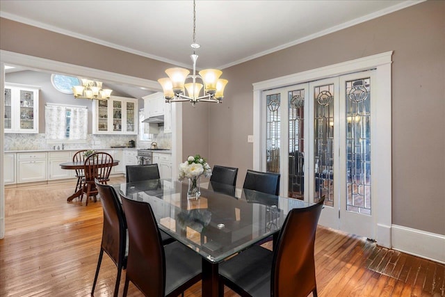 dining space with an inviting chandelier, ornamental molding, and light wood-type flooring