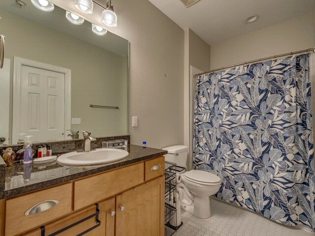 bathroom featuring vanity, walk in shower, tile patterned floors, and toilet