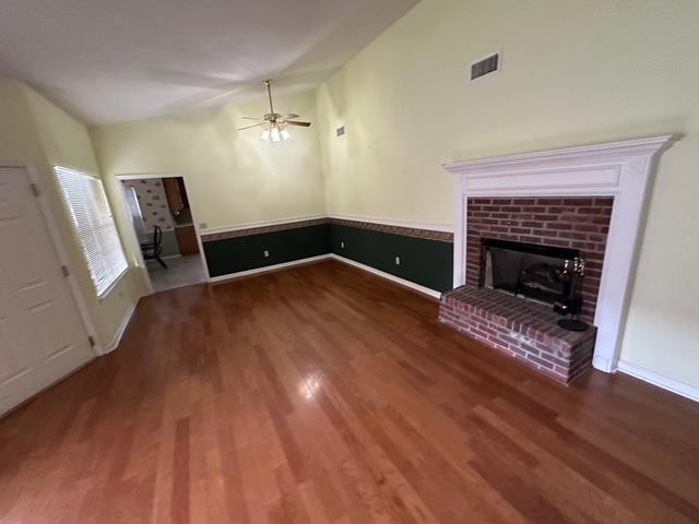 5356 Tewkesbury Trce, Tallahassee, FL 32309 - unfurnished living room featuring lofted ceiling, wood finished floors, ceiling fan, a brick fireplace, and baseboards