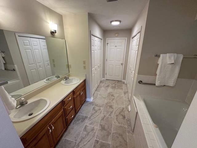 5356 Tewkesbury Trce, Tallahassee, FL 32309 - full bathroom featuring a closet, tiled bath, double vanity, and baseboards