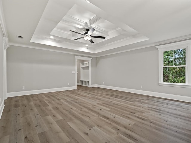 empty room featuring hardwood / wood-style floors, ceiling fan, a raised ceiling, and crown molding