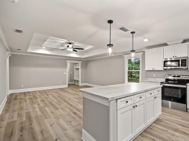 kitchen with ceiling fan, a center island, stainless steel appliances, a tray ceiling, and white cabinets