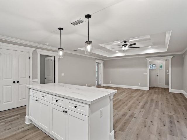 kitchen with white cabinets, crown molding, light wood-type flooring, a tray ceiling, and light stone counters