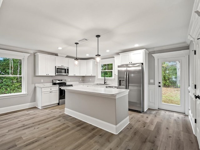 kitchen with sink, hanging light fixtures, stainless steel appliances, light hardwood / wood-style floors, and white cabinets