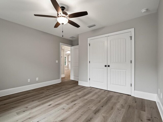 unfurnished bedroom featuring ceiling fan, a closet, and light hardwood / wood-style flooring