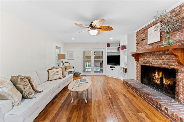 living room with light hardwood / wood-style floors, a brick fireplace, and ceiling fan