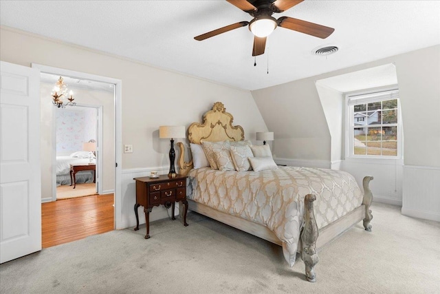 carpeted bedroom with lofted ceiling and ceiling fan with notable chandelier