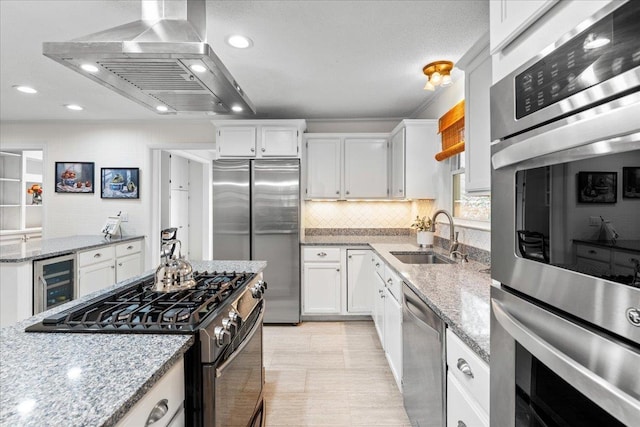 kitchen featuring white cabinetry, sink, wine cooler, island exhaust hood, and appliances with stainless steel finishes