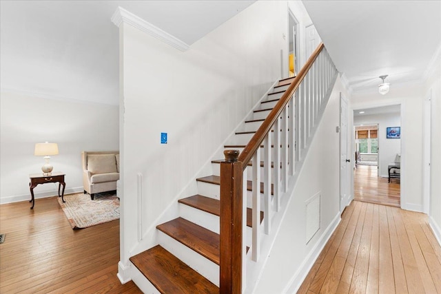 stairs featuring wood-type flooring and ornamental molding