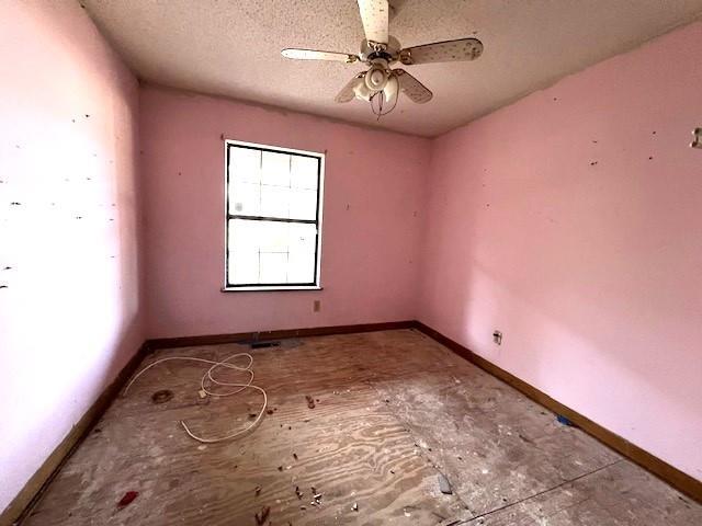 spare room featuring ceiling fan, a textured ceiling, and baseboards