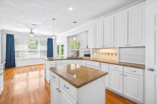 kitchen with a center island, light wood-type flooring, dishwasher, and a peninsula