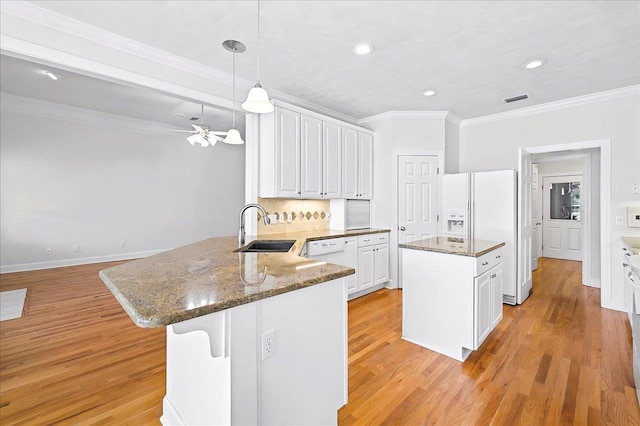 kitchen featuring a peninsula, white appliances, white cabinetry, a sink, and light wood-type flooring