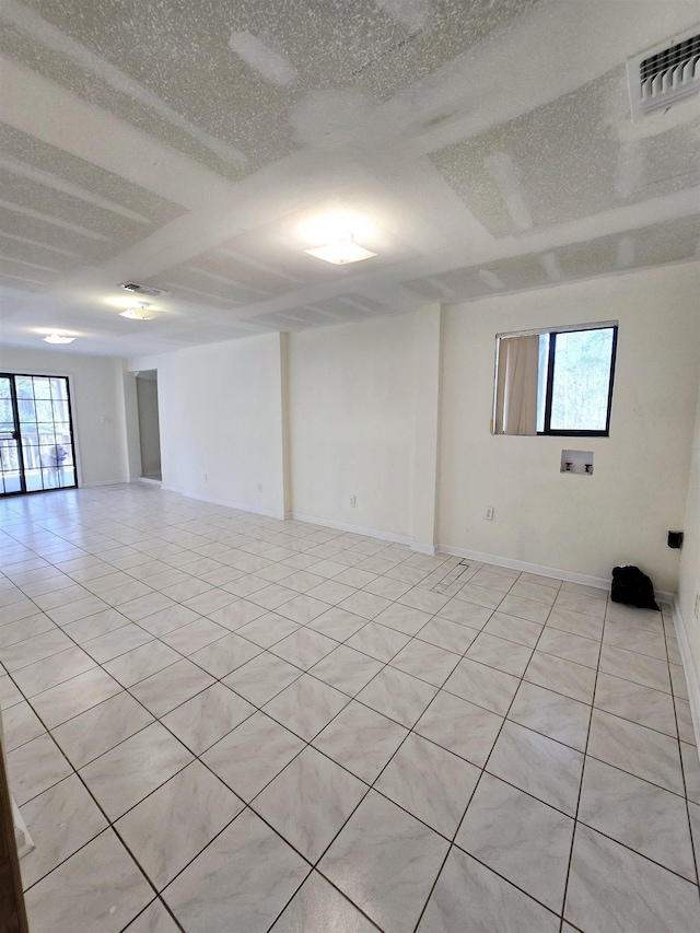 spare room featuring light tile patterned floors, visible vents, a textured ceiling, and baseboards